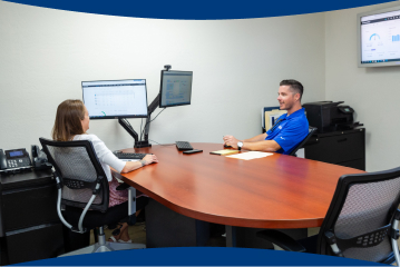 A customer sits at a desk across from an employee from Christian Brothers reviewing a monitor with informationA customer sits at a desk across from an employee from Christian Brothers reviewing a monitor with information
