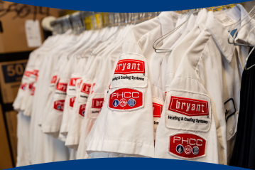 HVAC technician uniforms hanging in a row with the Bryant red logo on the sleeves